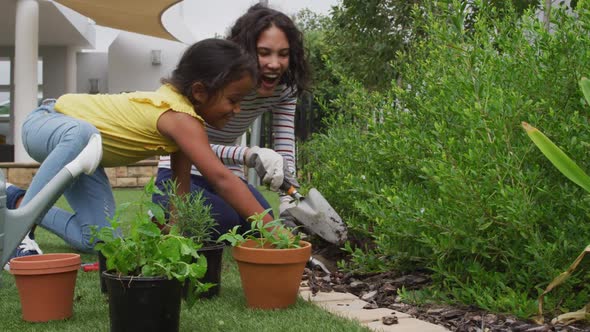 Hispanic mother and daughter teaching planting flowers in the garden