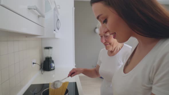 Smiling Woman Helping Grandmother To Cook