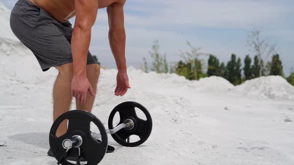 Athlete is taking heavy barbell on the natural background.