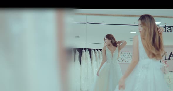 Beautiful Girl Tries on a Wedding Dress in Front of a Mirror in the Salon. Dress Sparkles in