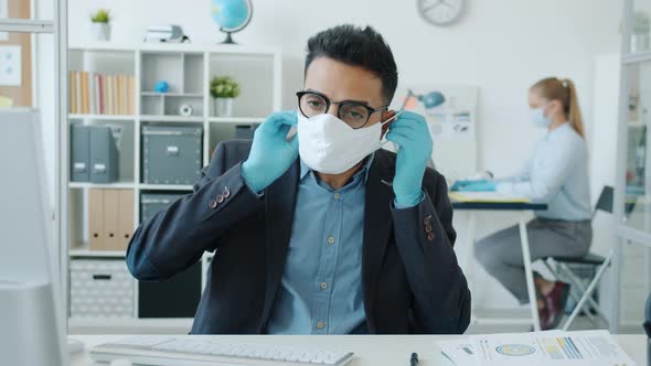 Portrait of Arab Man Putting on Facial Medical Mask in Office During Epidemic alt