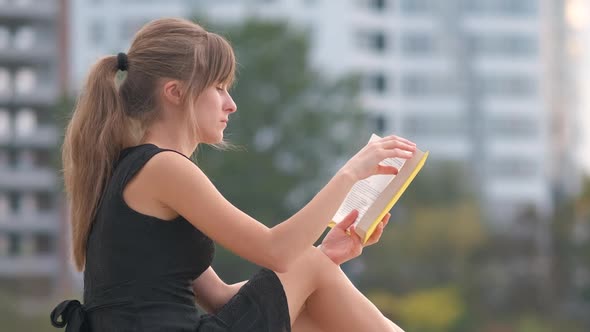 Female Student Sitting in Summer Park Reading Textbook Outdoors