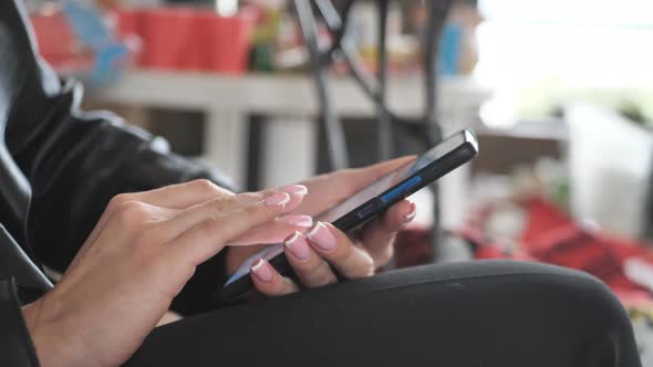 Hand of a Young Woman Using a Mobile Phone Reads a Phone Message or Downloads a Smartphone App