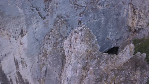 Climber stands on high peak after ascending and looks out on amazing landscape of Turda Gorge on Sky