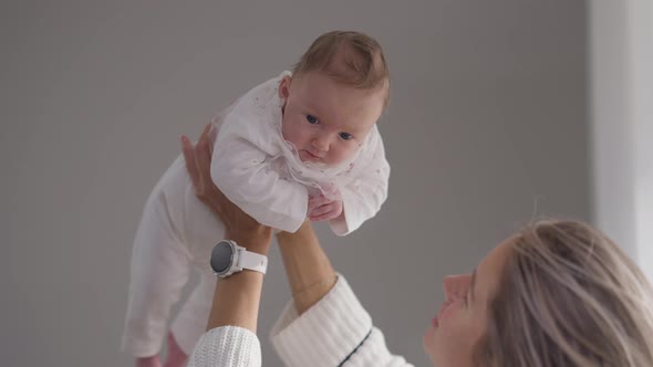 Cheerful Caucasian Infant Girl in Hands of Young Mother Talking in Slow Motion