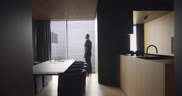 A Man Looks Out the Window Into a Apartment with an Modern Kitchen Interior