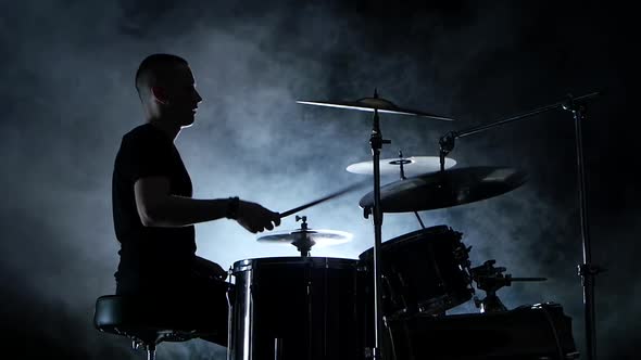 Energetic Musician Plays Good Music on Drums, Black Smoky Background, Side View, Silhouette