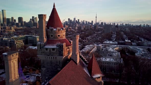 Drone Reveal - Toronto Skyline behind Casa Loma Tower at Winter Sunset. Establishing Wide Shot of Do