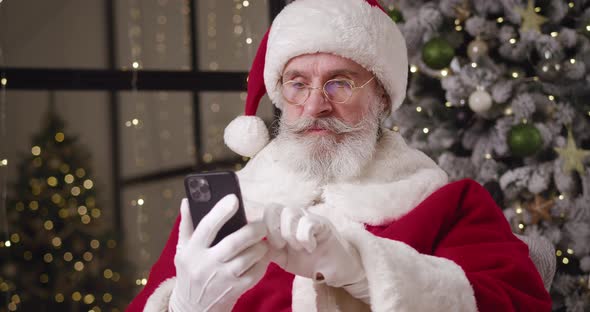Handsome Kind Santa Claus Browsing Websites Swiping Surfing on Internet Using Smartphones and