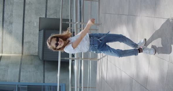 Joyful Girl in Stylish Look and Glasses Dancing and Having Fun on Urban Area