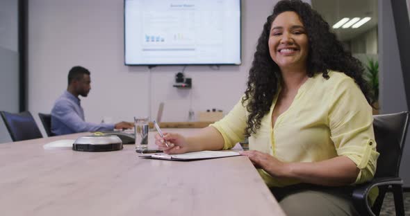 Portrait of smiling biracial businesswoman looking at camera in modern office