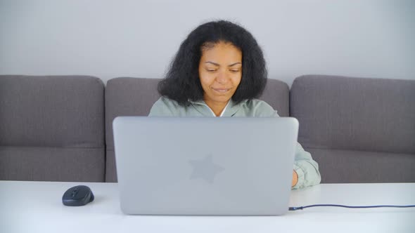 Black woman doing distant work on laptop computer at home during lockdown