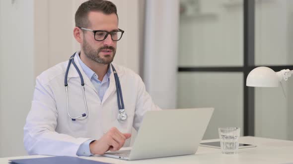 Male Doctor Talking on Video Call on Laptop in Hospital