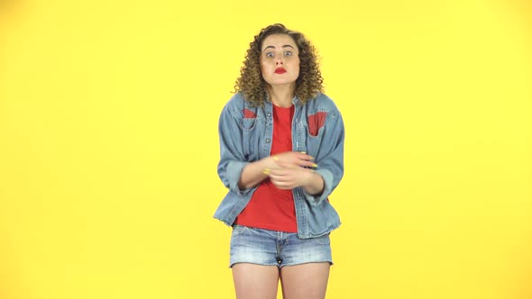 Girl Is Angry, Waving Her Hands in Indignation, Shrugs on Yellow Background at Studio