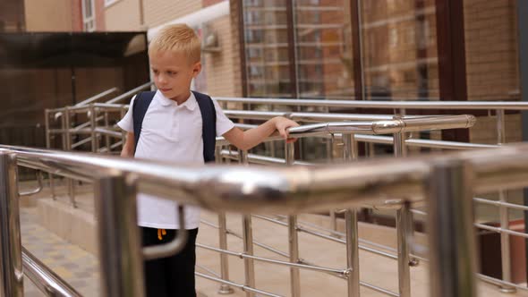 A Little Boy with a Backpack on His Back Goes to School in the Morning