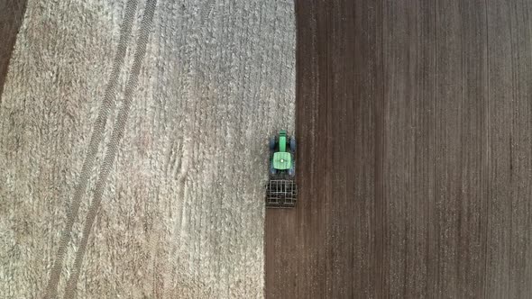Green tractor plowing field on spring, view from drone, Poland alt