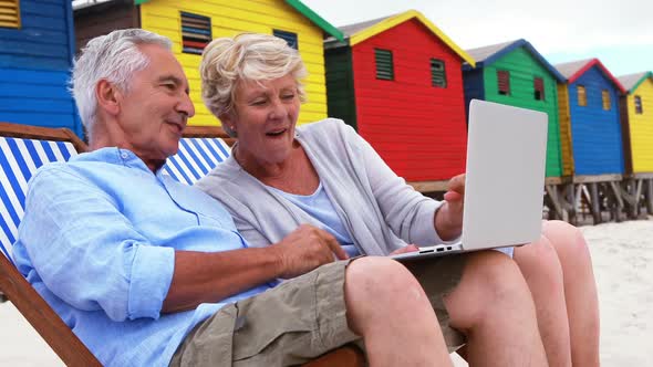 Senior couple using laptop at the beach