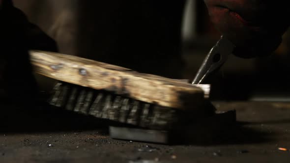 Hands of welder using wire brush on a piece of metal