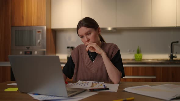 A Brooding Woman Looks Into a Computer Monitor While Working From Home