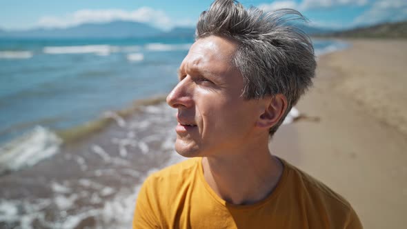 Close Up Portrait of Middle Aged Greyhead Man at Sea Coast Enjoys Sunny Day and Fresh Air on