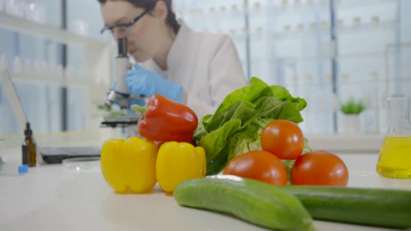 Fresh Vegetables in the Laboratory Against the Background of a Scientist Looking Through a