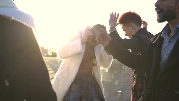 Zoom Out From Caucasian Man with Smartphone in Sunrays to Dancing Group of Friends on Rooftop at