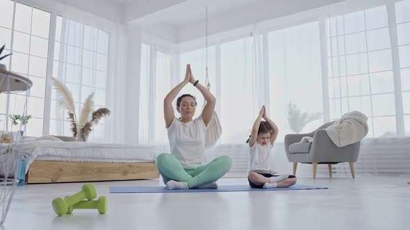 Cute Little Girl Practicing Yoga with Mom Indoors