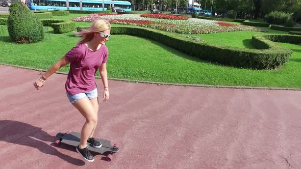 Smiling blonde woman longboarding in the city