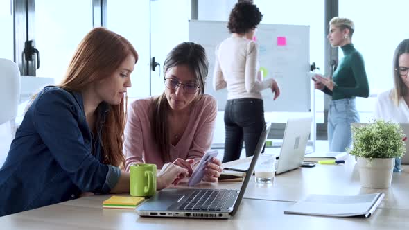 Slow motion shot of businesswomen using smartphone during meeting