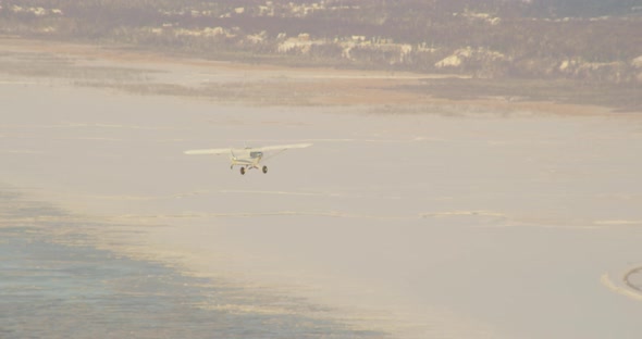 Aerial helicopter shot tilt up from snowy Alaskan plateau towards mountains in distance, drone foota