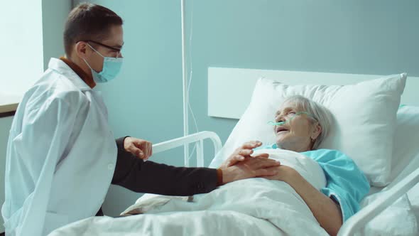 Man in Mask Visiting Senior Mother in Hospital