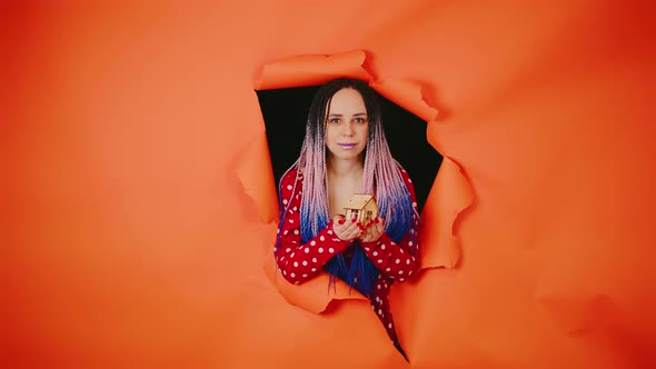 Woman with Toy House Looking Through Hole in Paper