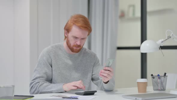 Beard Redhead Man Using Calculator While Counting Dollars