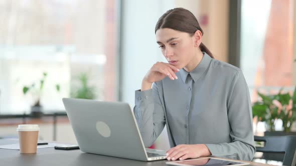 Young Latin Woman Thinking While Using Laptop at Work