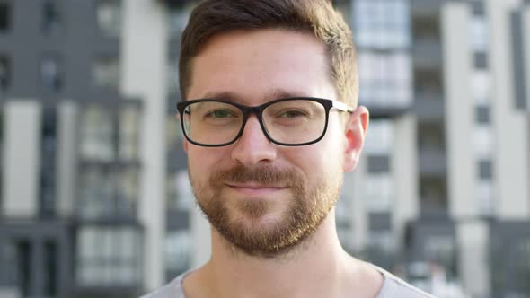 Young Man With Beard In Glasses. He Smiles.