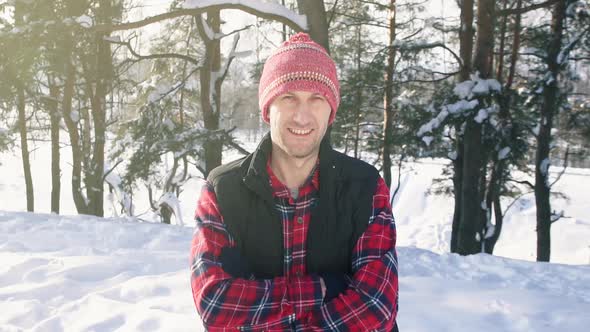 Portrait of a Smiling Man in a Red Shirt and Hat in a Winter Forest