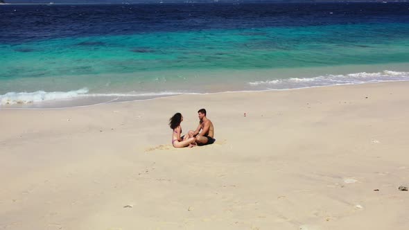 Boy and girl engaged on paradise island beach lifestyle by aqua blue water and white sand background