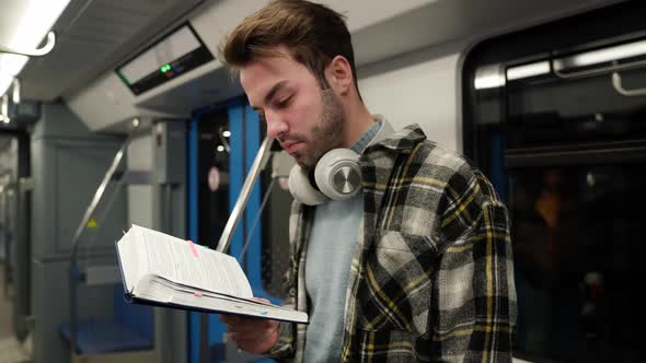 Handheld Young Man Rides the Subway and Reads a Book a Student Goes to Study at the University