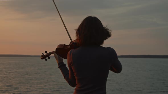 Woman Is Playing Violin On Lakeshore