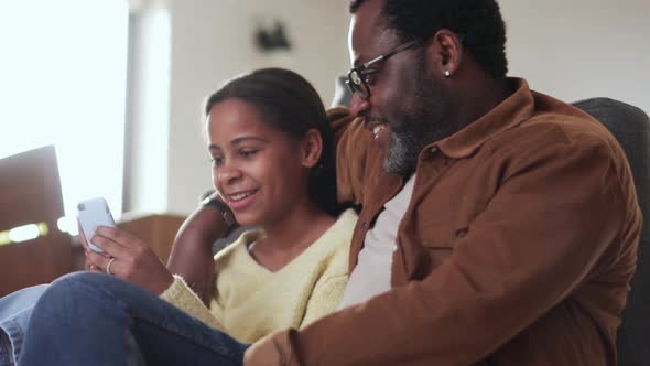 Positive father and daughter looking at phone and talking