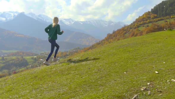 the camera follows a young beautiful woman who runs uphill down a slope