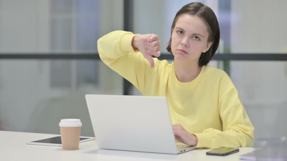 Young Woman Showing Thumbs Down Sign While Using Laptop in Office