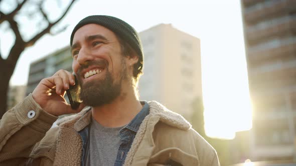 Laughing bearded man wearing hat talking by phone