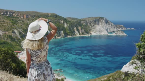 Blond Woman Wearing Sun Hat is Looking at Beautiful Sea Bay Enjoying Scenic Landscape Enjoying