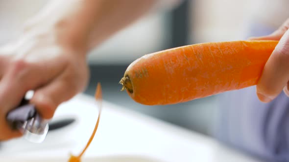 Hands Peeling Carrot with Vegetable Peeler