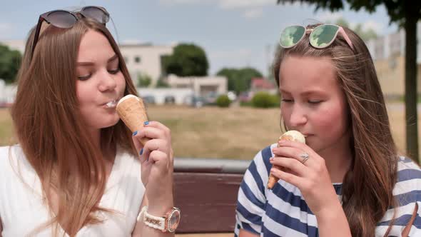 Two Girls Friends Eating Ice Cream on the Street of the City