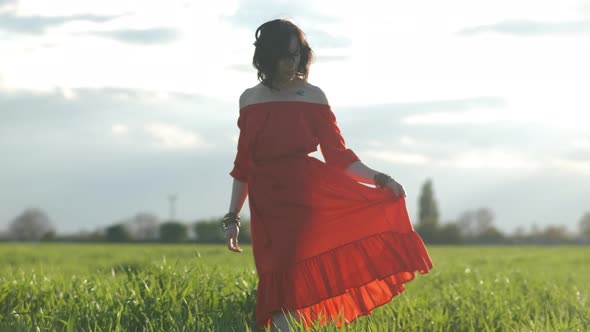 Portrait of a Beautiful Spanish Brunette Woman in a Red Dress at Sunset in a Wheat Field
