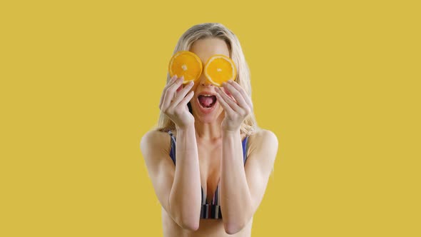 Young Beautiful Girl Is Smiling with Oranges in Hands on an Yellow Background. Happy Healthy Skinny