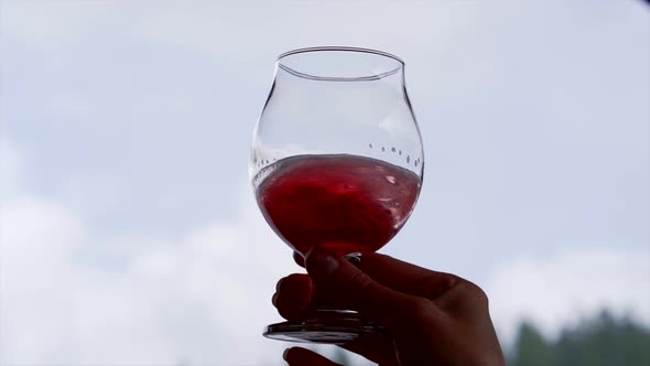 Glass of wine swirling slow motion with the sky in the background.