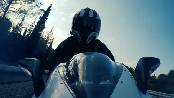 POv shot of a man riding on a white sports motorcycle on a curved road